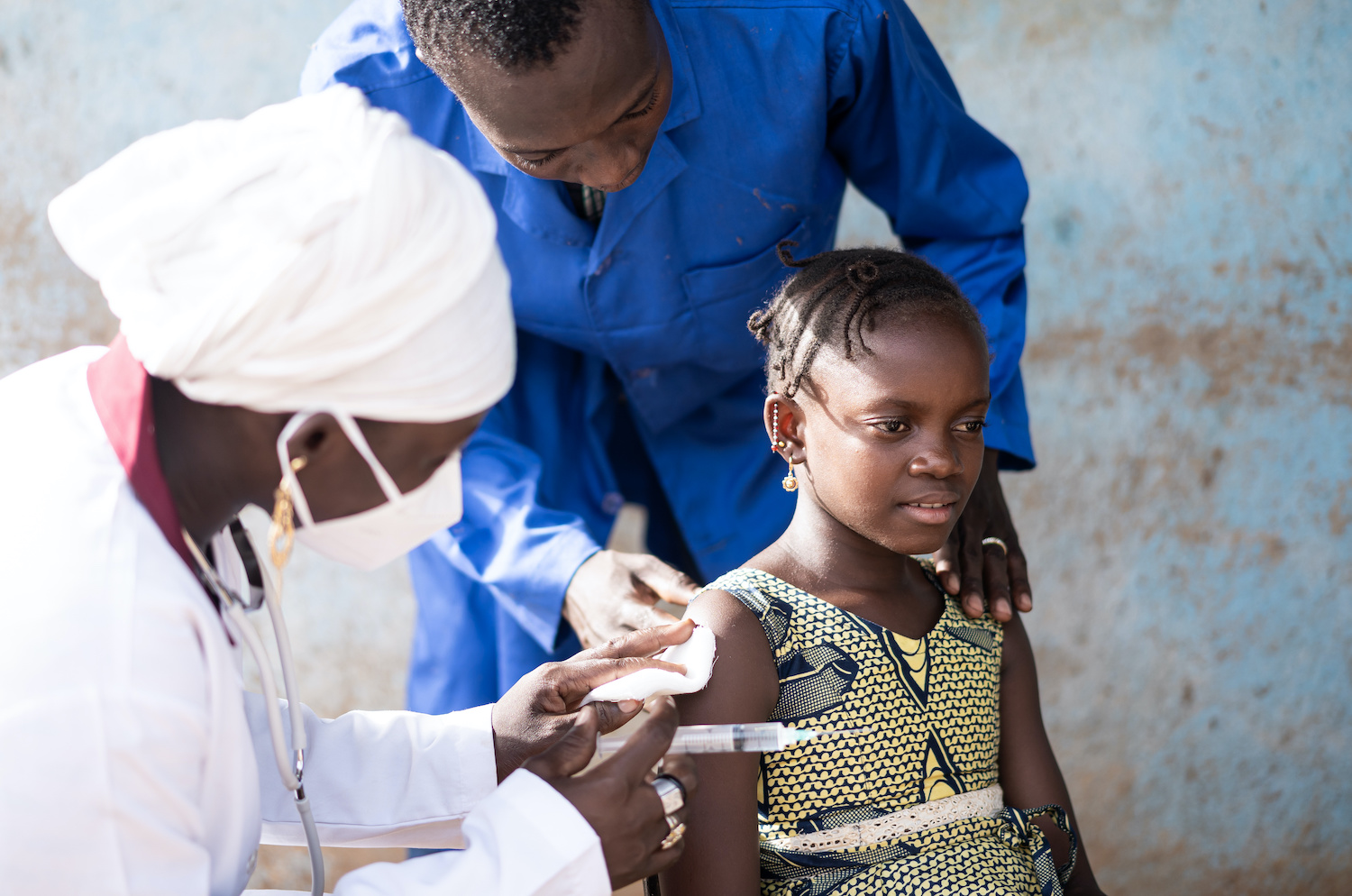 In this image, a relieved little African girl is looked after by the vaccination staff after she has received her first Covid shot. Source: Riccardo Mayer