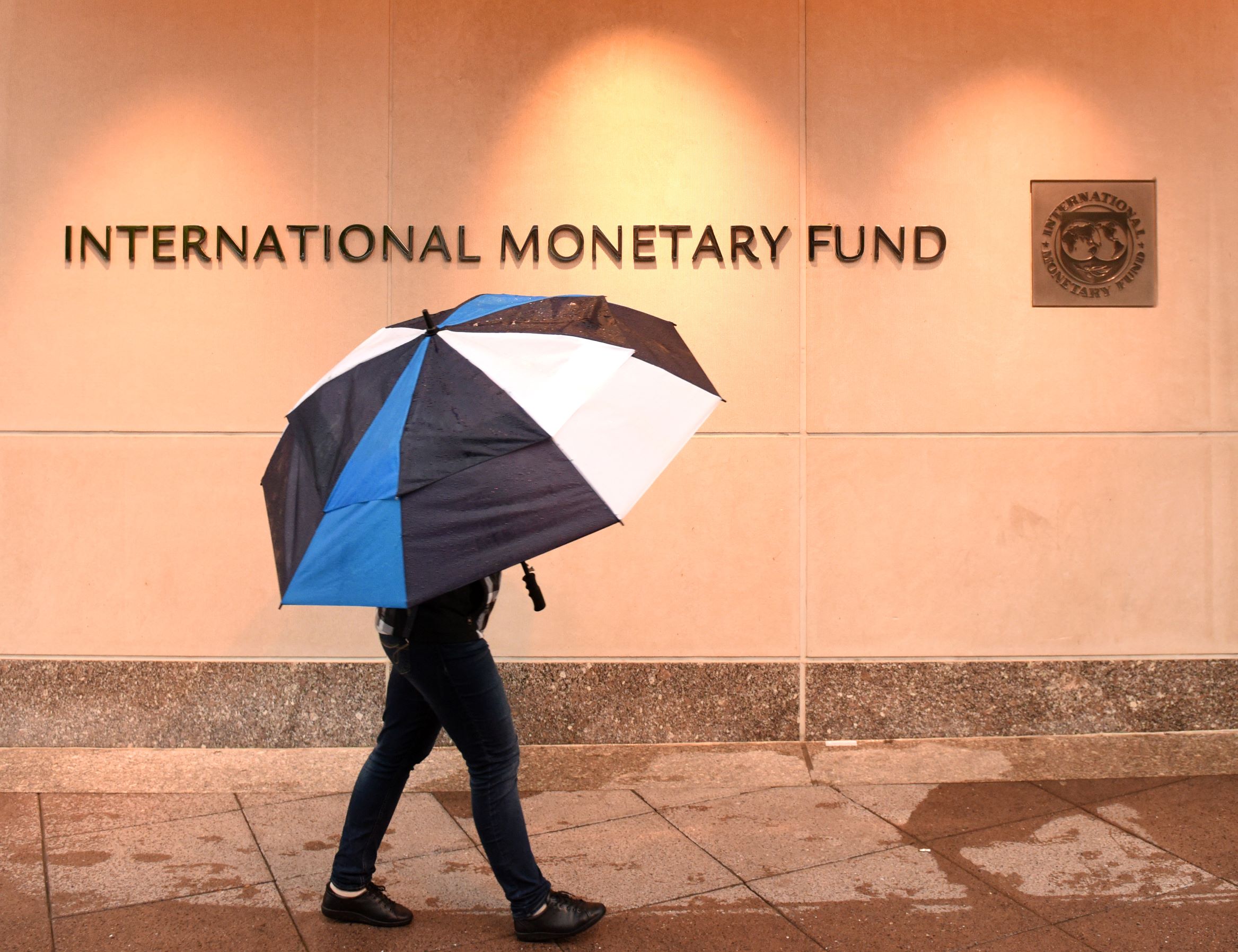 Person walking past the IMF building with an umbrella