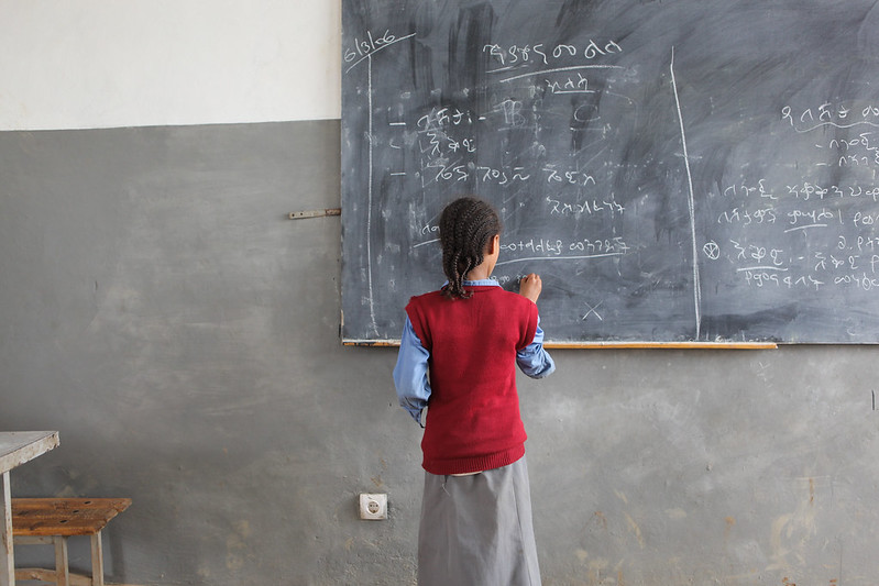 Girl at blackboard shown from the back