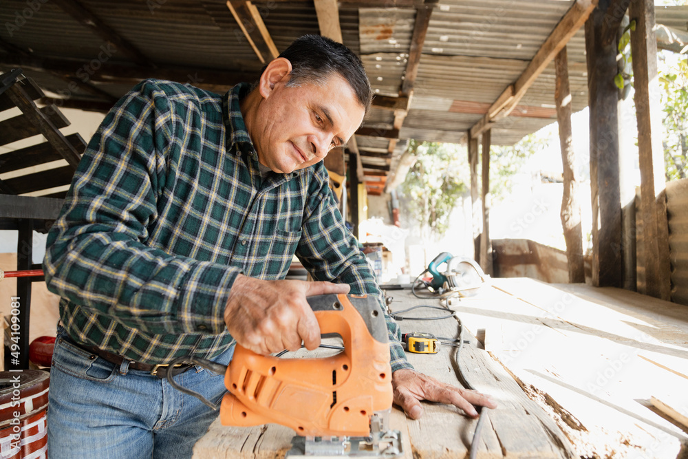 man sawing a plank of wood on a construction site