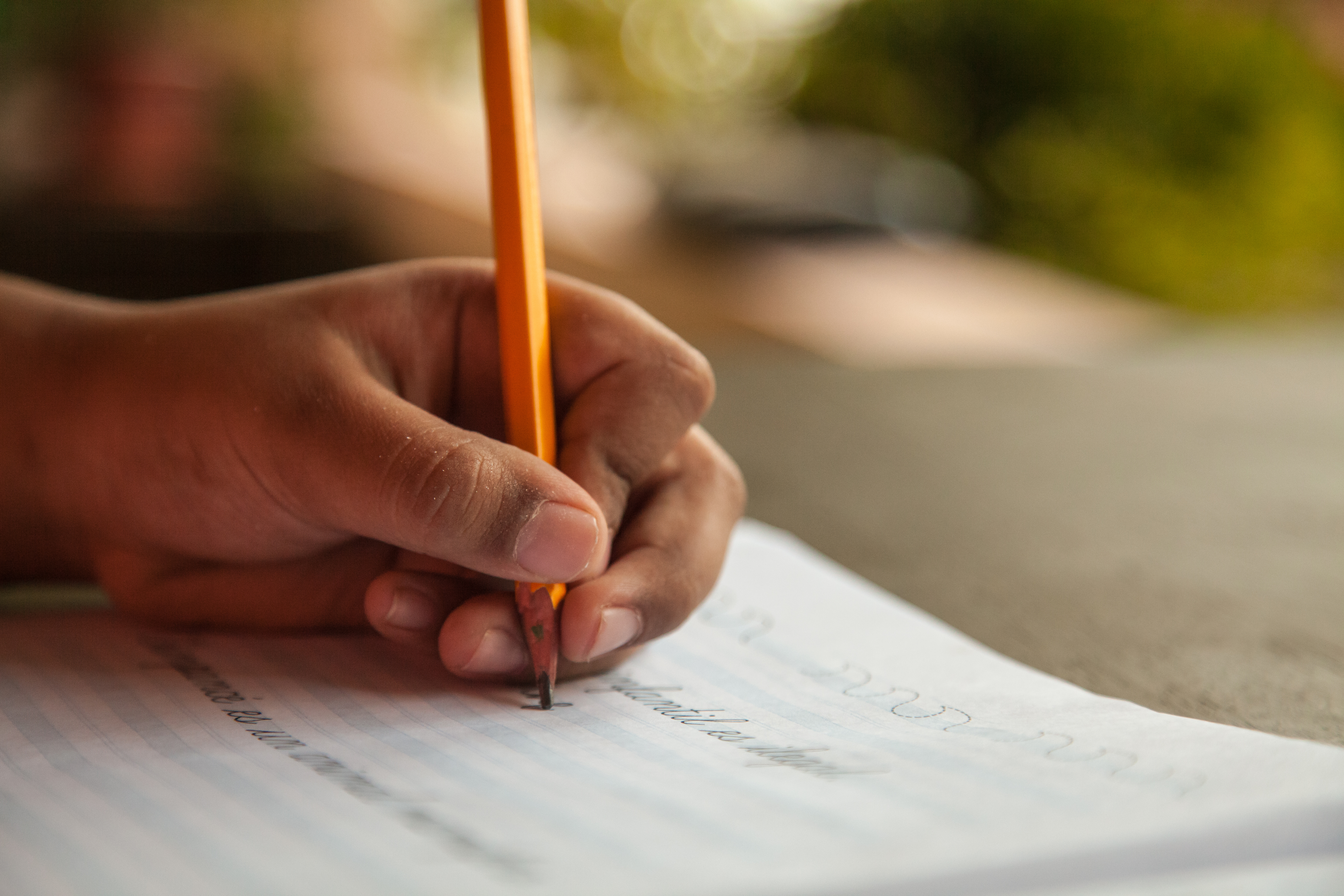 student hand with pencil and workbook