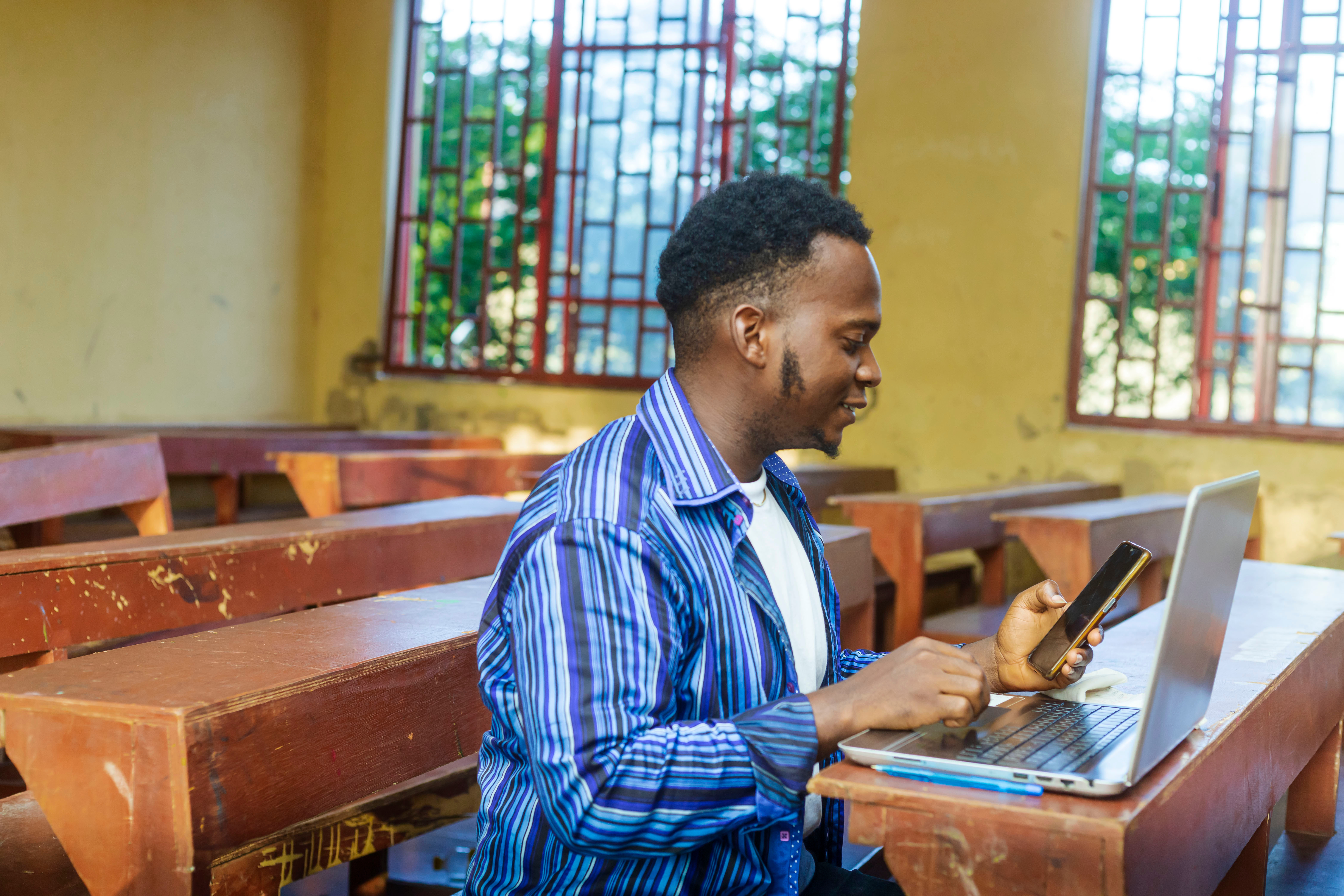 teacher with laptop and cell phone in African classroom