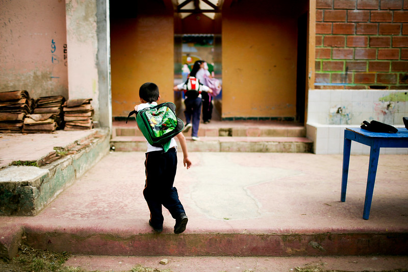 boy with backpack running into classroom