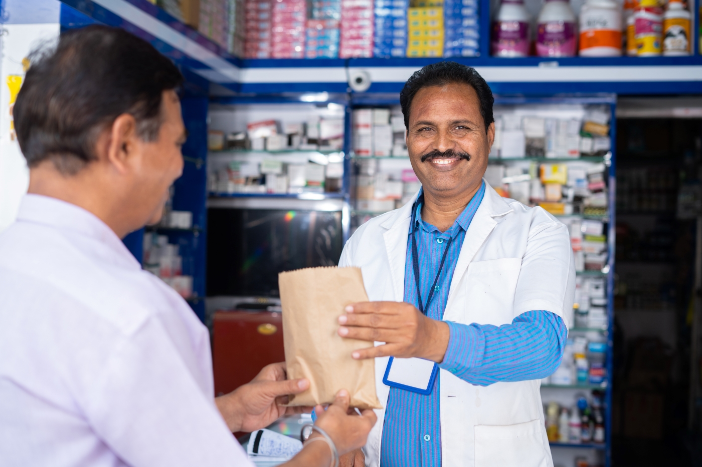 Pharmacist in India handing a bag to a customer