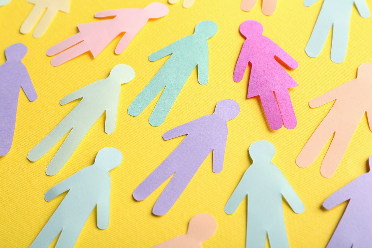Many different paper human figures on yellow background. 