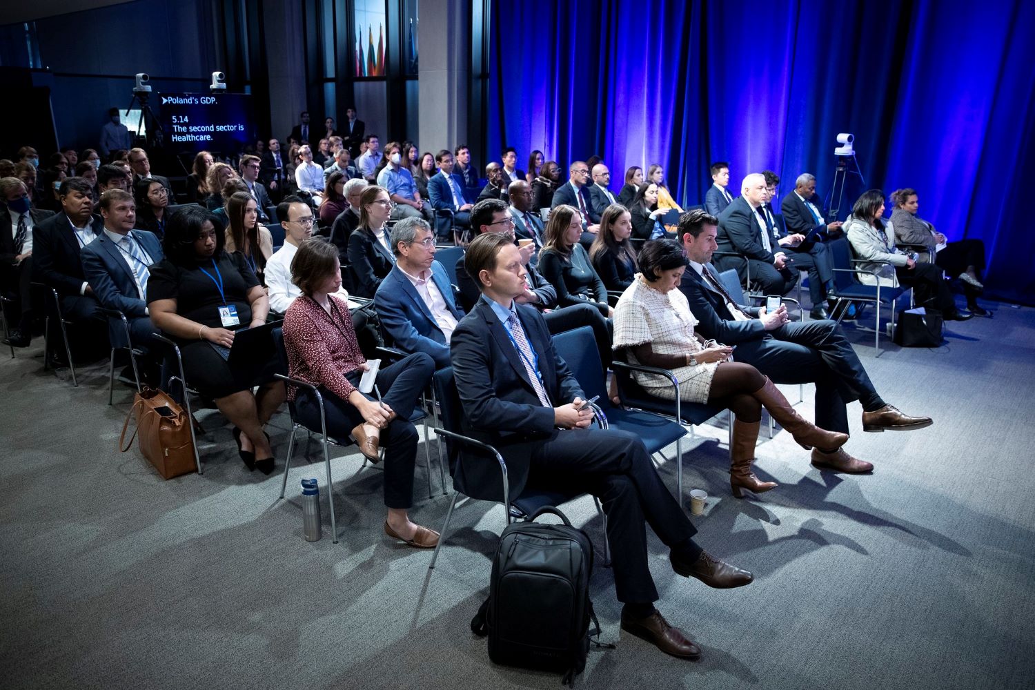 Audience members watch as Nicolo Bird Presents the Analytical Corner titled Policies to support refugees from Ukraine in Europe during the 2022 Annual Meetings at the International Monetary Fund.