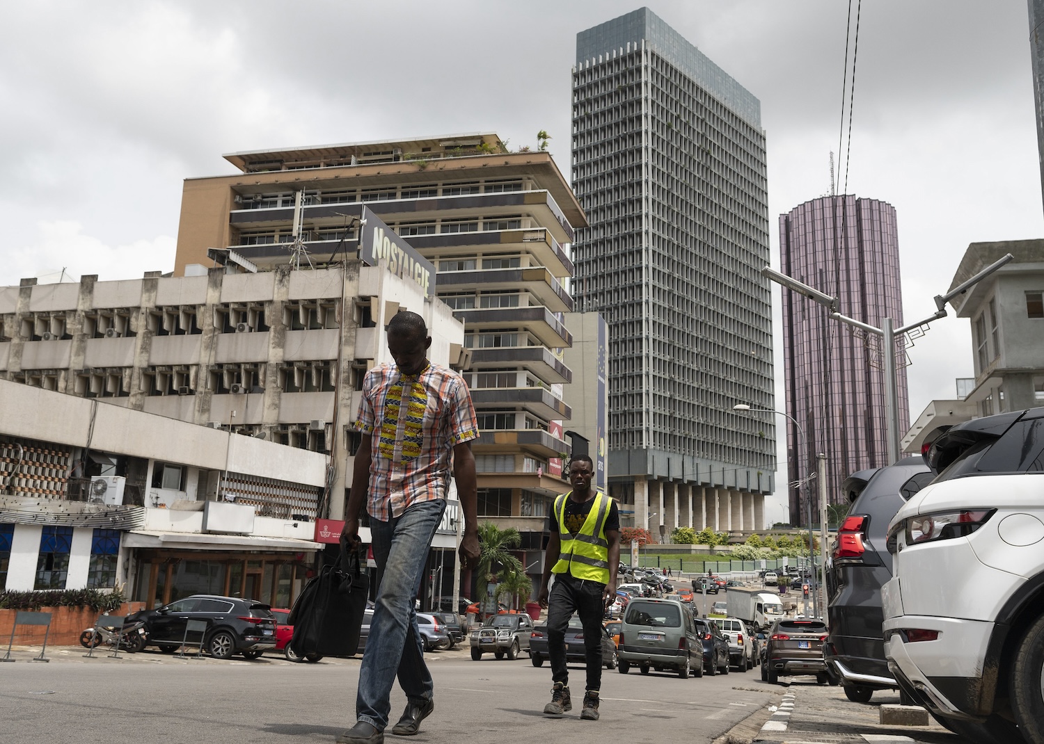 Two men walk up the road, with government buildings seen in the background, in the Plateau financial district in Abidjan, Cote d'Ivoire on April 4, 2022.