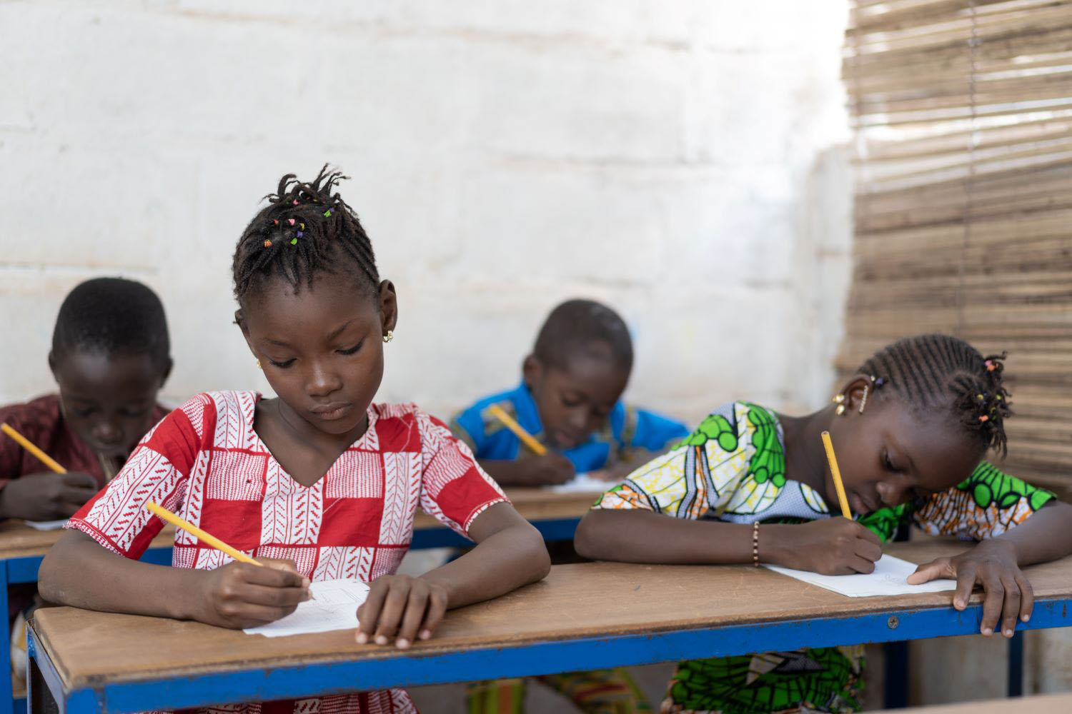 Four children sitting at school desk, working. 