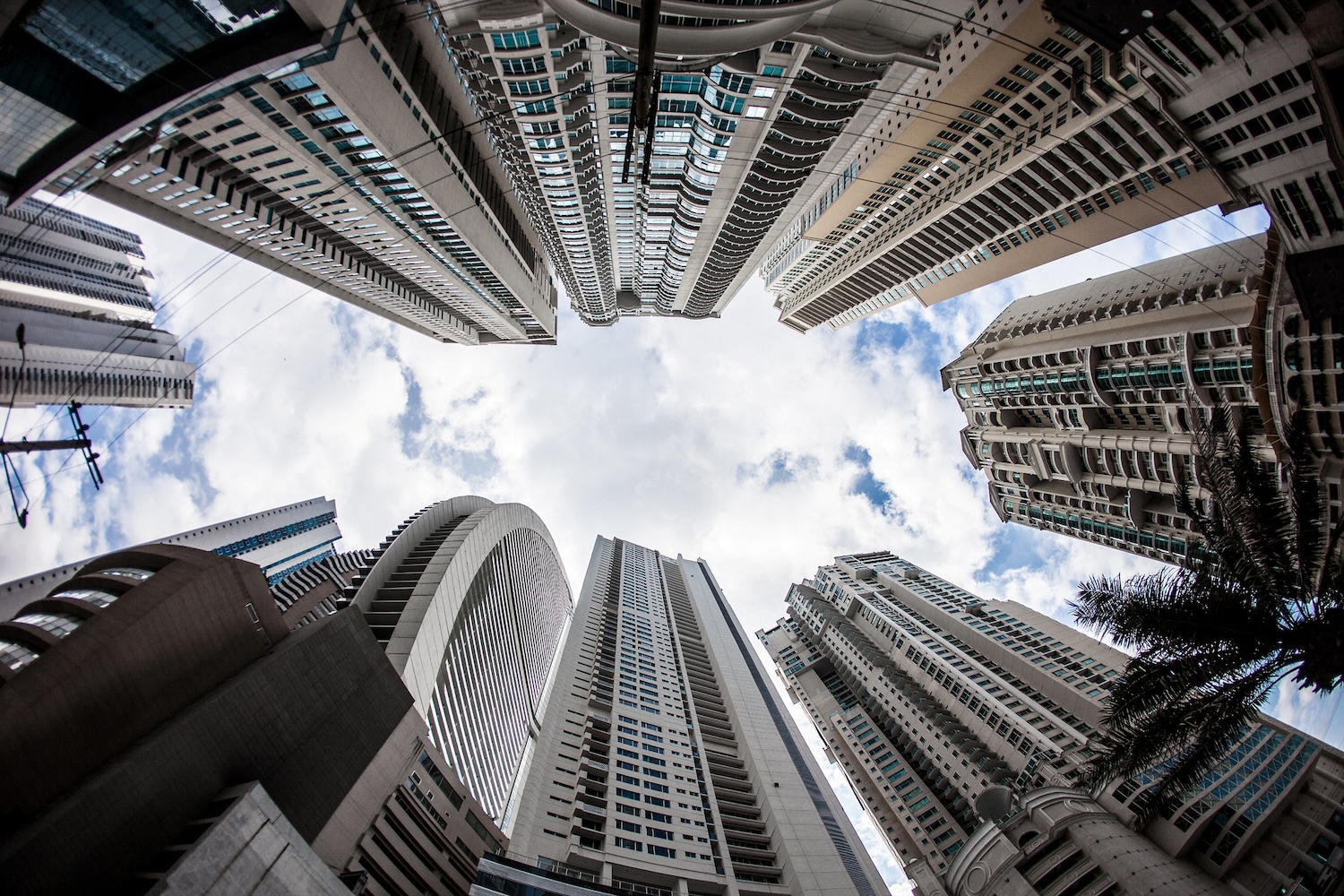 View from below of the sky hemmed in by a number of skyscrapers