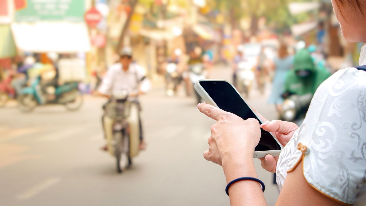 Woman using mobile phone on Vietnamese street with traffic motorcycles