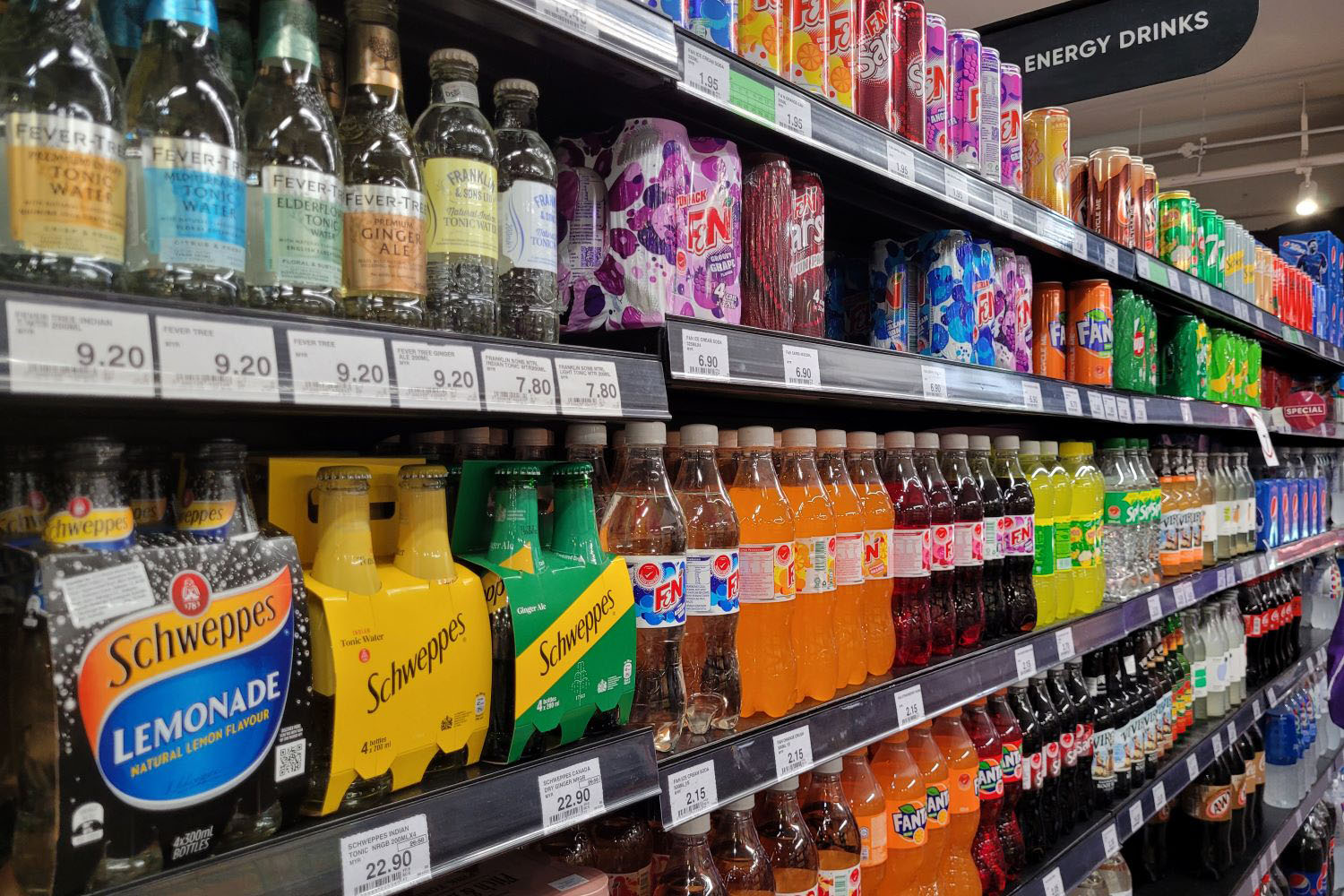  Various brands of canned soft drinks are displayed on the open refrigerator shelves in a grocery store in Malaysia.