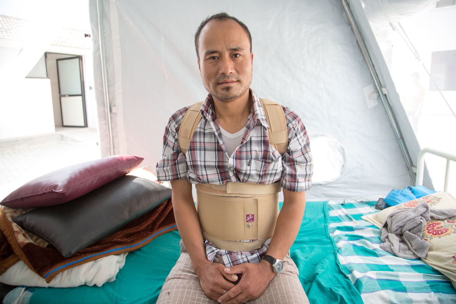 Man sitting on bed with cast for back