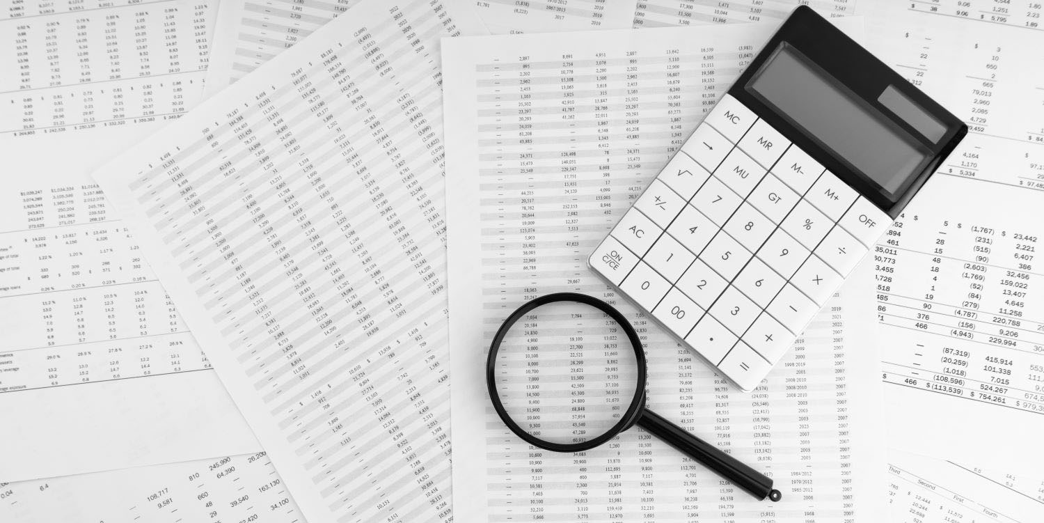 Calculator and magnifying glass on financial statement.