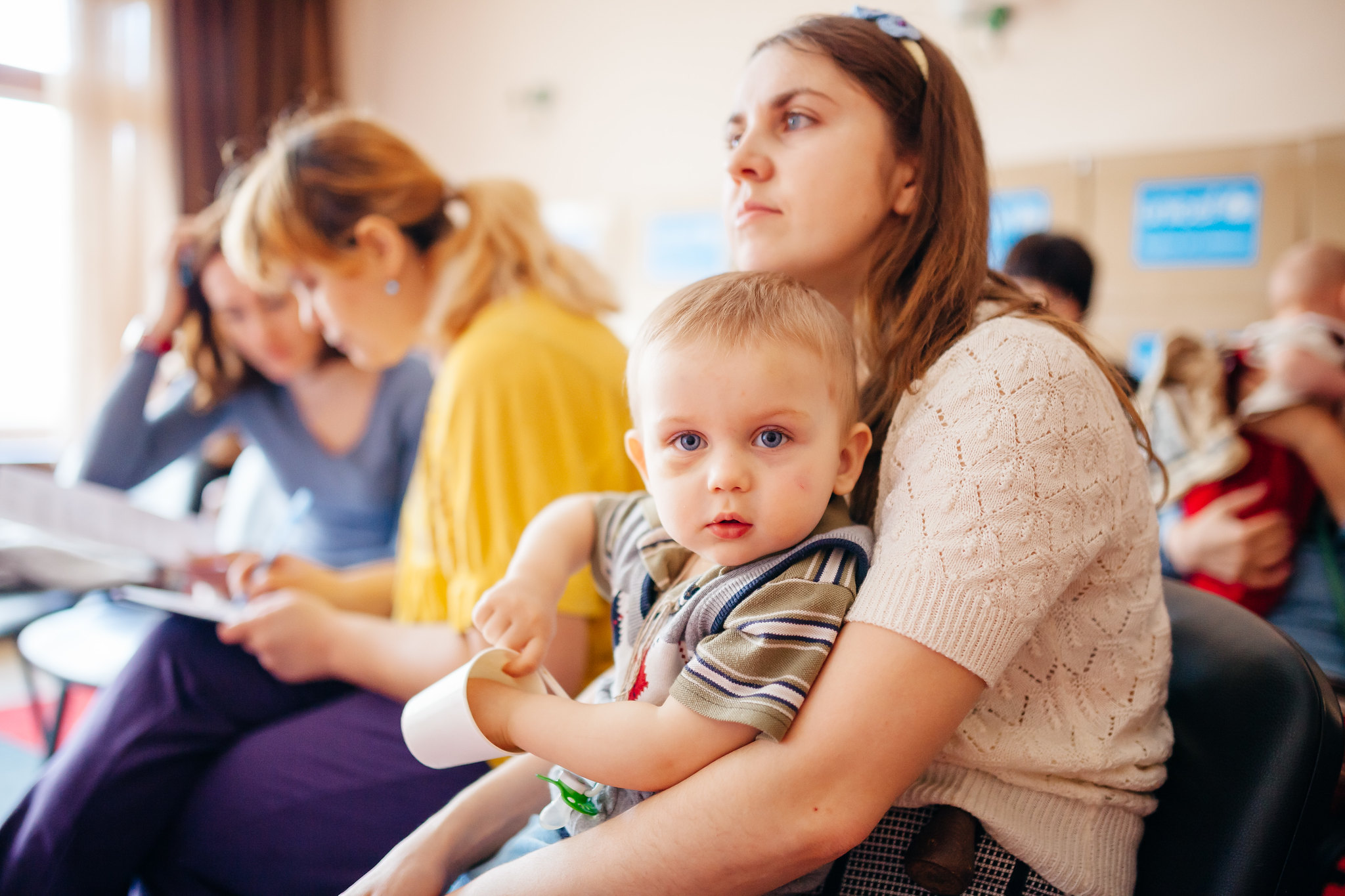 Women in room hold children on their laps