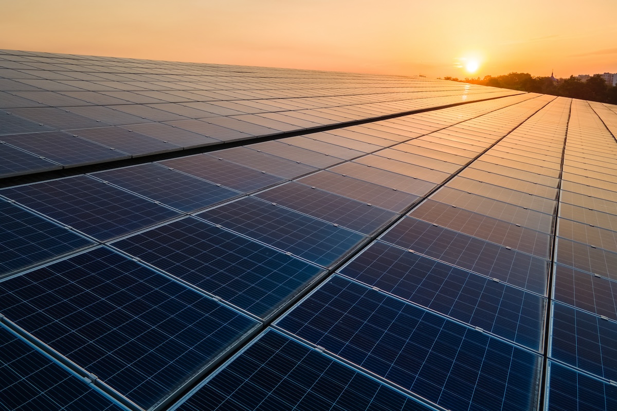 Stock photo of a sun rising over a set of solar panels