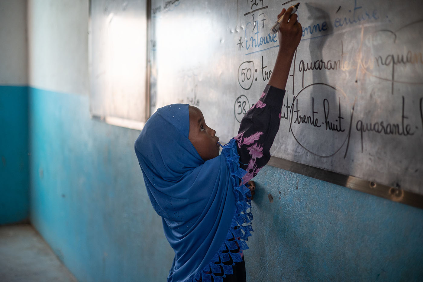 Schoolgirl in Djibouti writing on a chalkboard 