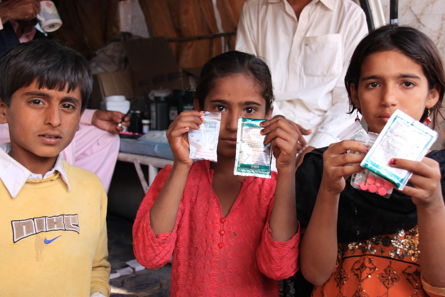 Children in Sindh, Pakistan, hold up medicines that prevent sickness and diarrhea