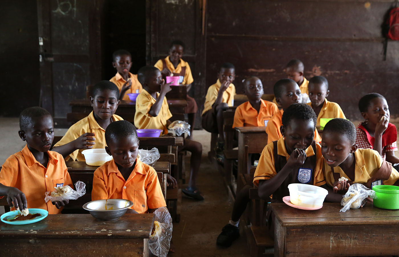 Students enjoy a warm meal in their classroom at Kanda Estate Primary School in Accra, Ghana