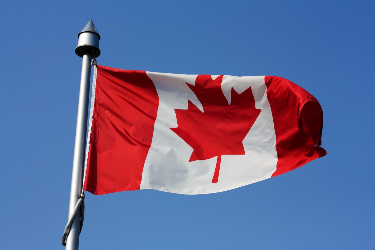 Canadian flag on pole moving with the wind