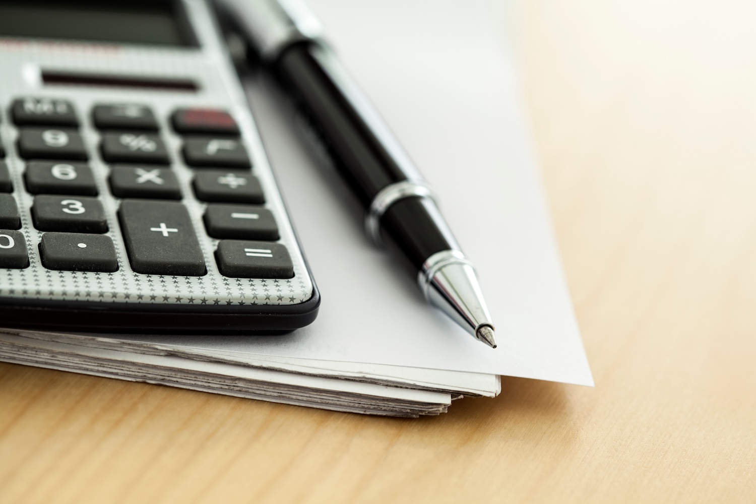 Calculator and pen on top of a stack of paper