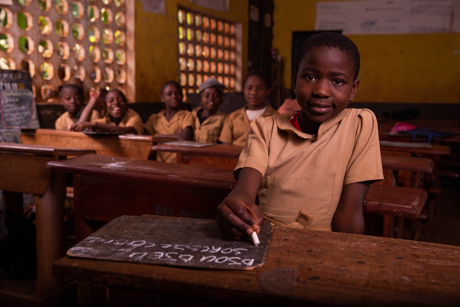 School-aged students seated at tables in a classroom, engaging in learning activities.