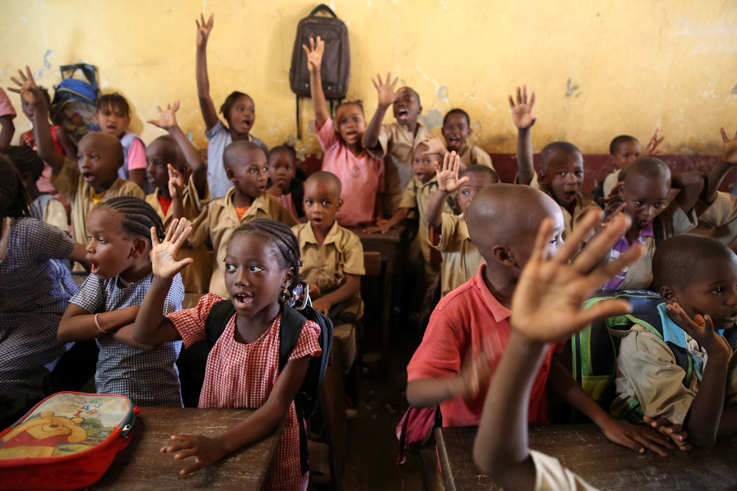 Children raises their hands to answers a teachers questions at the Wodia Berete School in Conakry, Guinea.