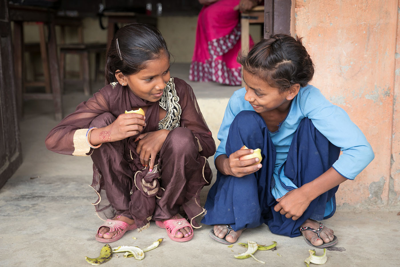 Girls in Nepal share a snack outside a classroom
