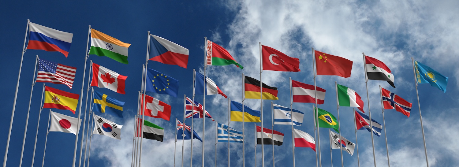 Flags from various countries waving across a blue sky