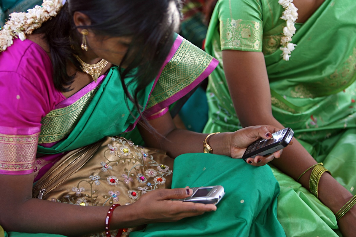 A woman using a phone at a community meeting in Aurangabad, India