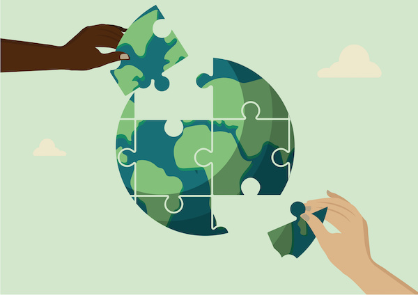 Two hands collaborate to complete a puzzle shaped like the Earth