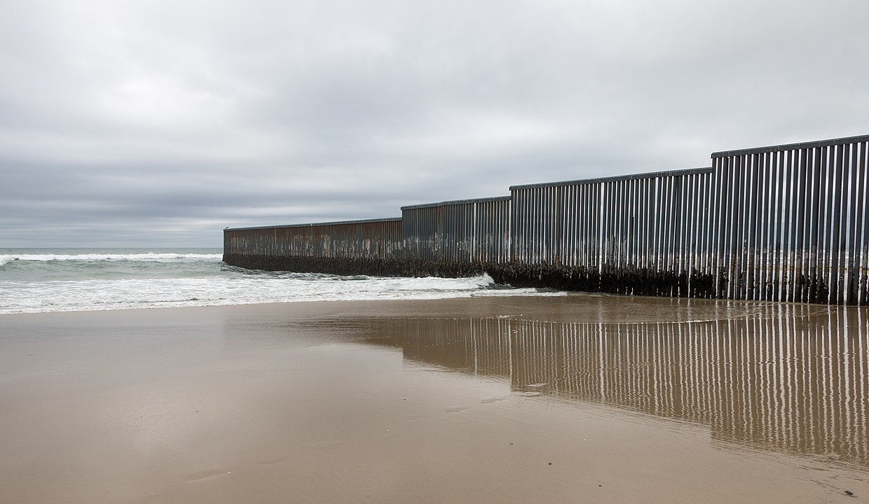 US Mexico border wall on beach going out to Pacific Ocean