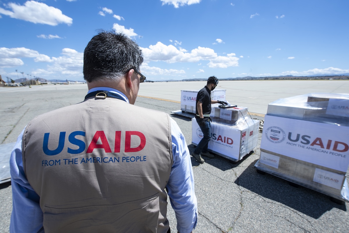 A USAID official oversees emergency supplies being loaded at the tarmac