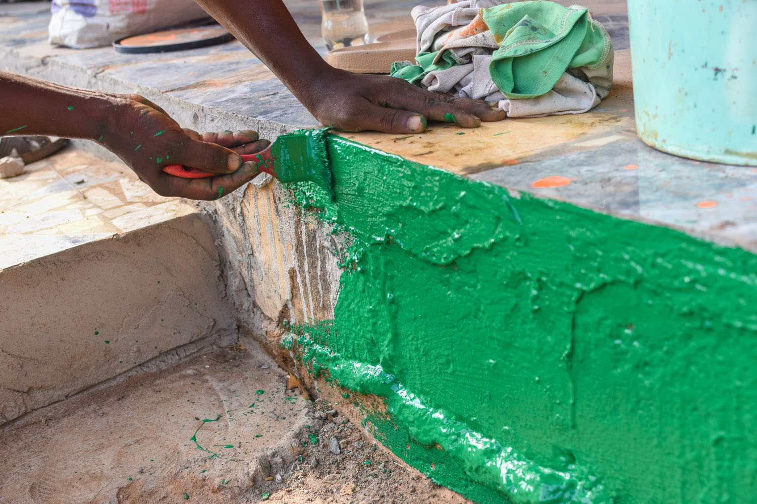 Hand of an african painter painting the section of a wall with the help of a paint brush