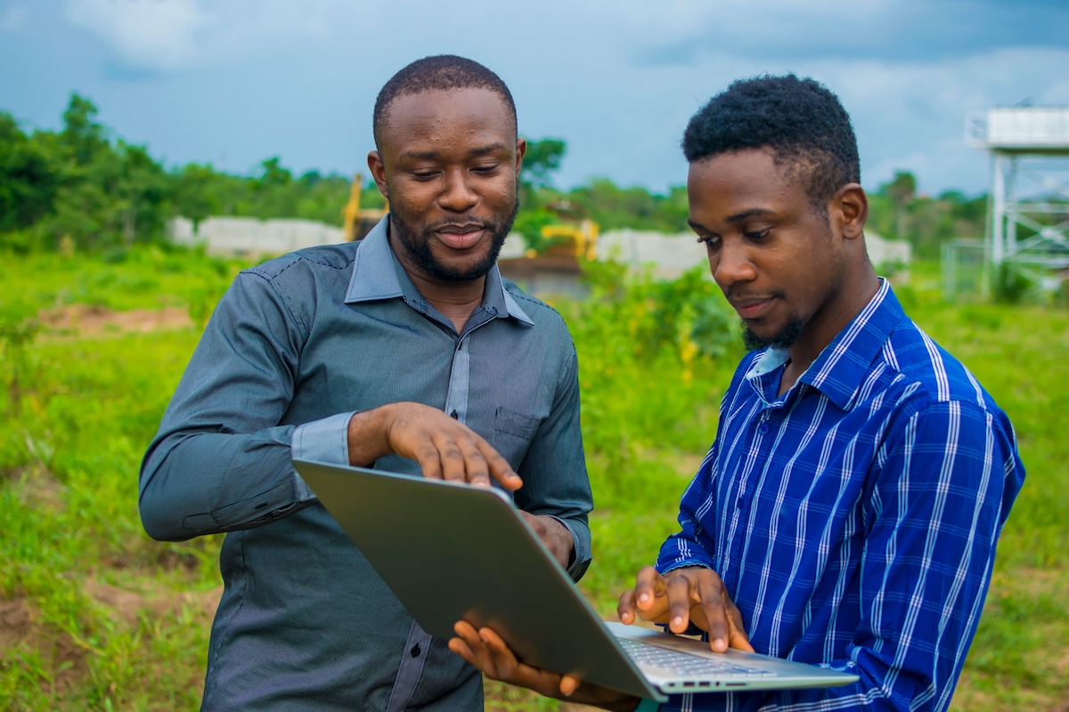 Two men with a laptop in a field