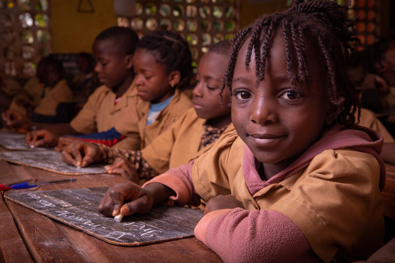 Chidren in a classroom taking notes on a blackboard