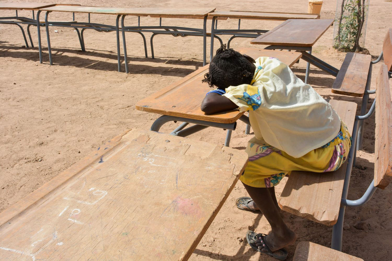 Student in outdoor classroom with her head on a desk 