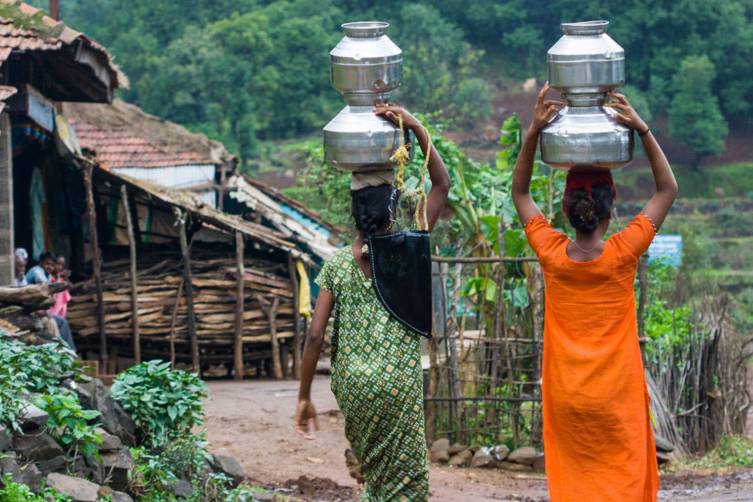 Two women carrying water on their heads in a remote village