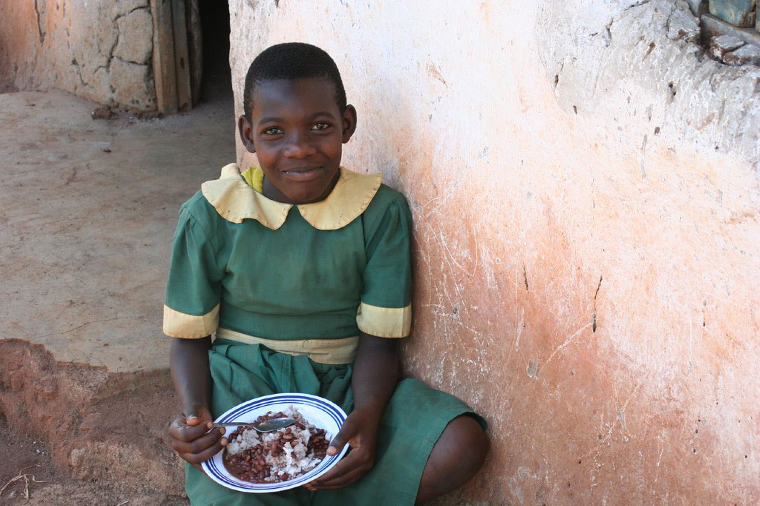 African student in uniform eating a school lunch. 