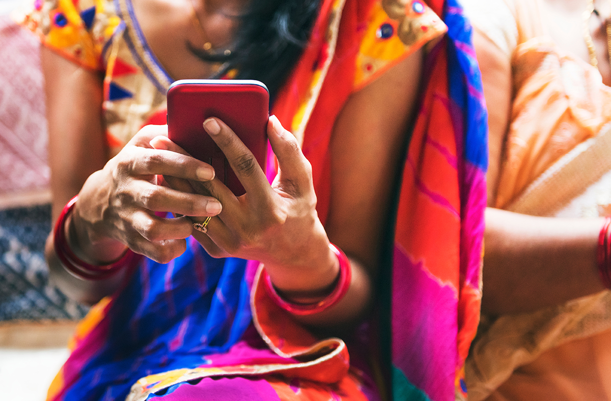 Woman dressed in a sari holds a mobile phone