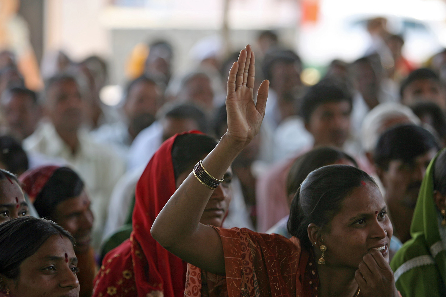A woman raises her hand to speak at a community meeting in Aurangabad