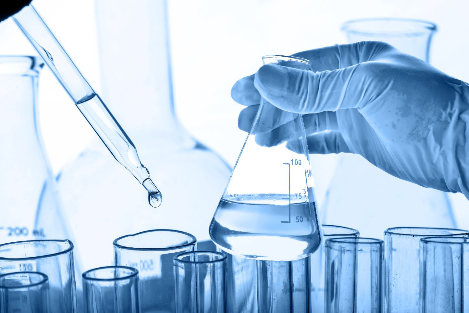 Flask in scientist hand with lab glassware background