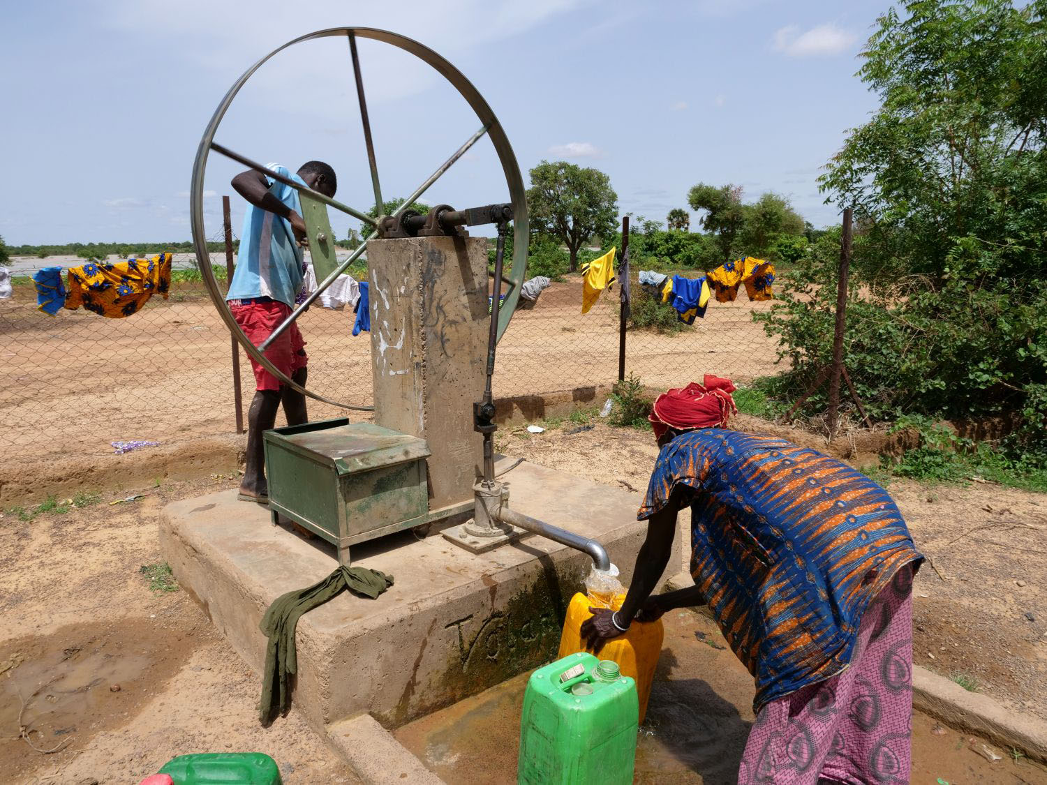 Woman in Africa getting water from a tap 