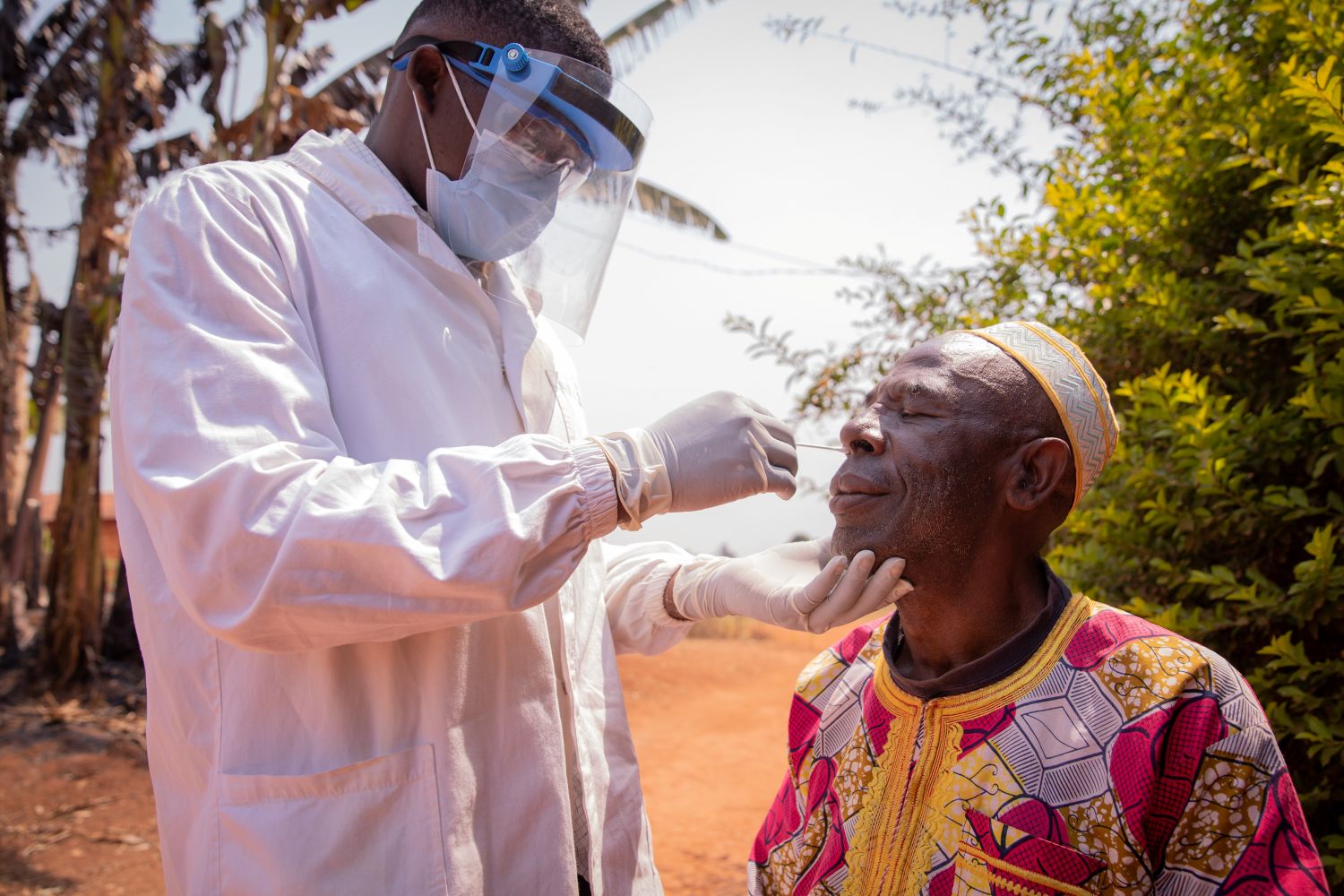 A doctor performs a test with a swab on an elderly African patient.