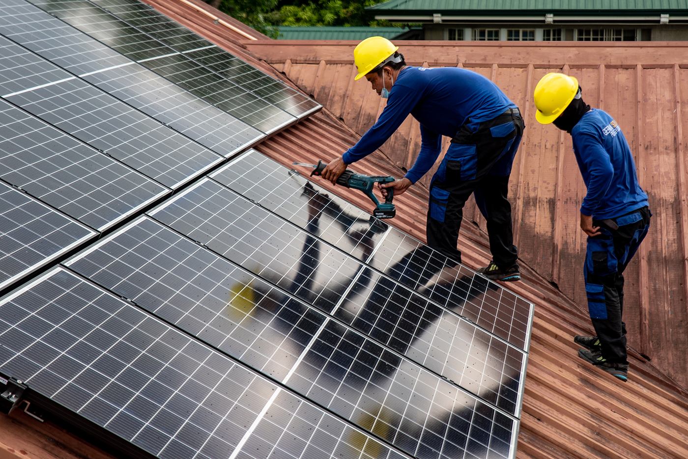 Workers from PHILERGY, a German-Filipino supplier and installer of solar energy, install solar panels at a house in Manila