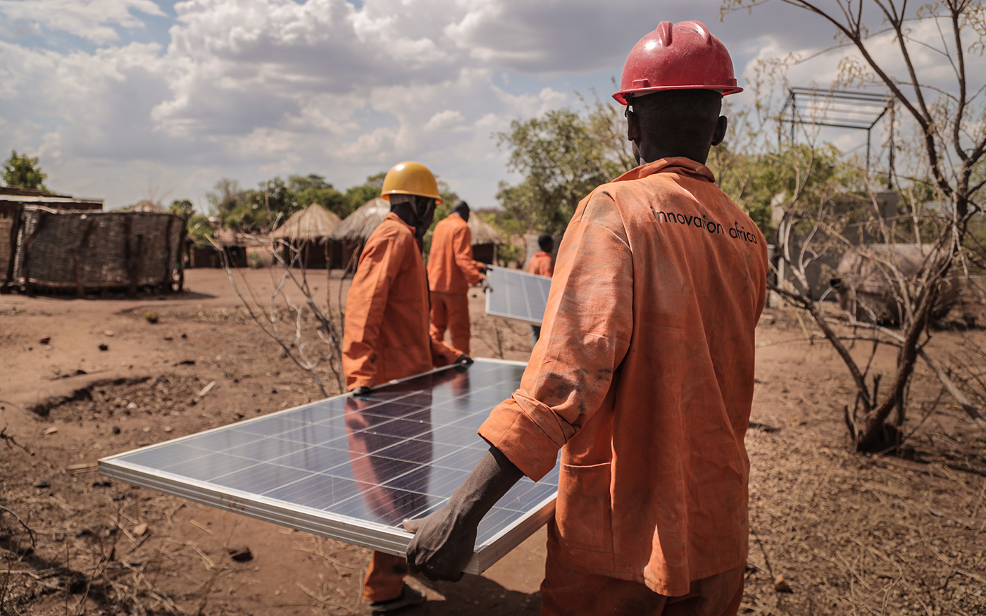 Men carrying solar panels in African village