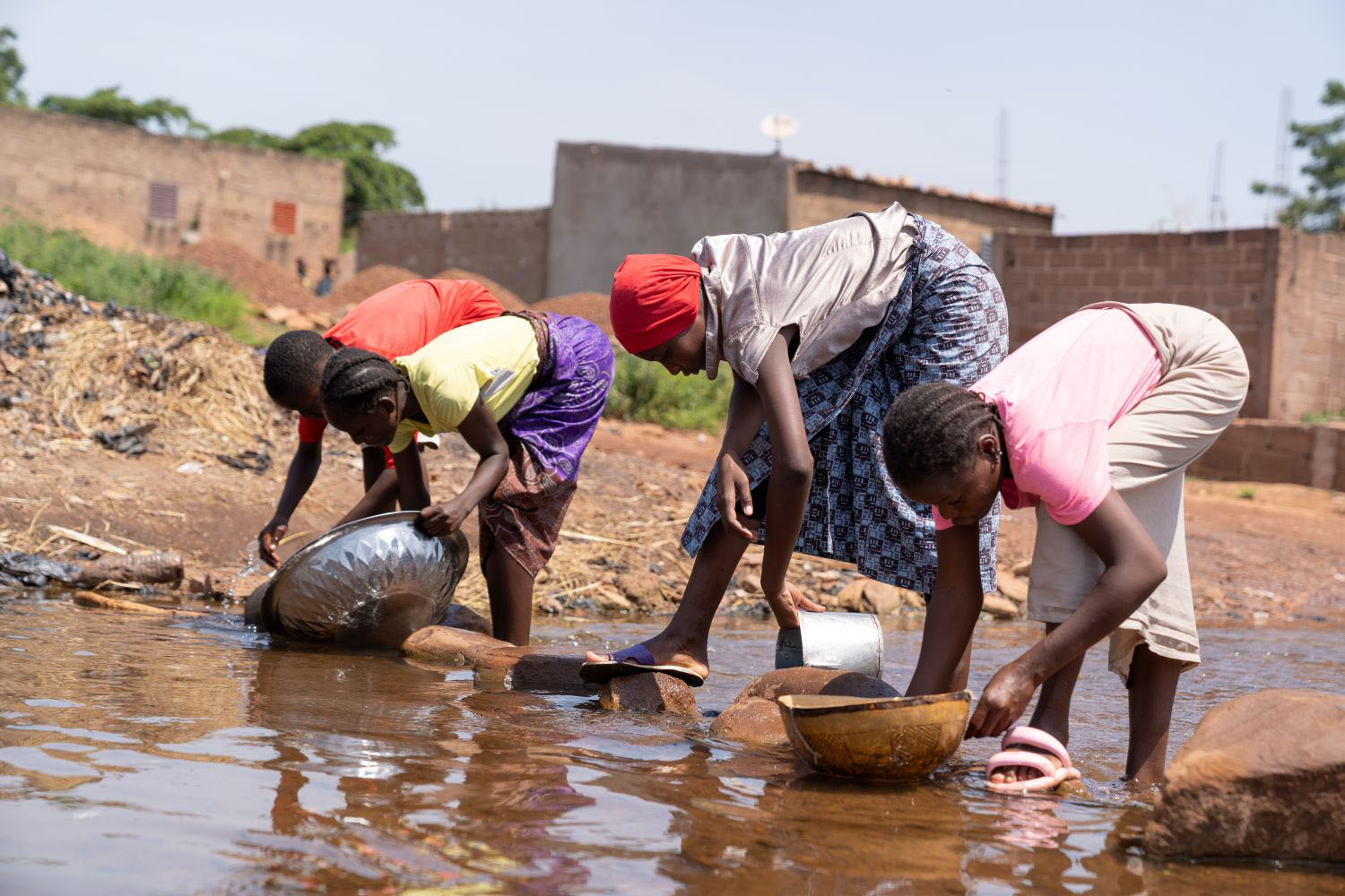 Group of West African girls washing dishes in a river