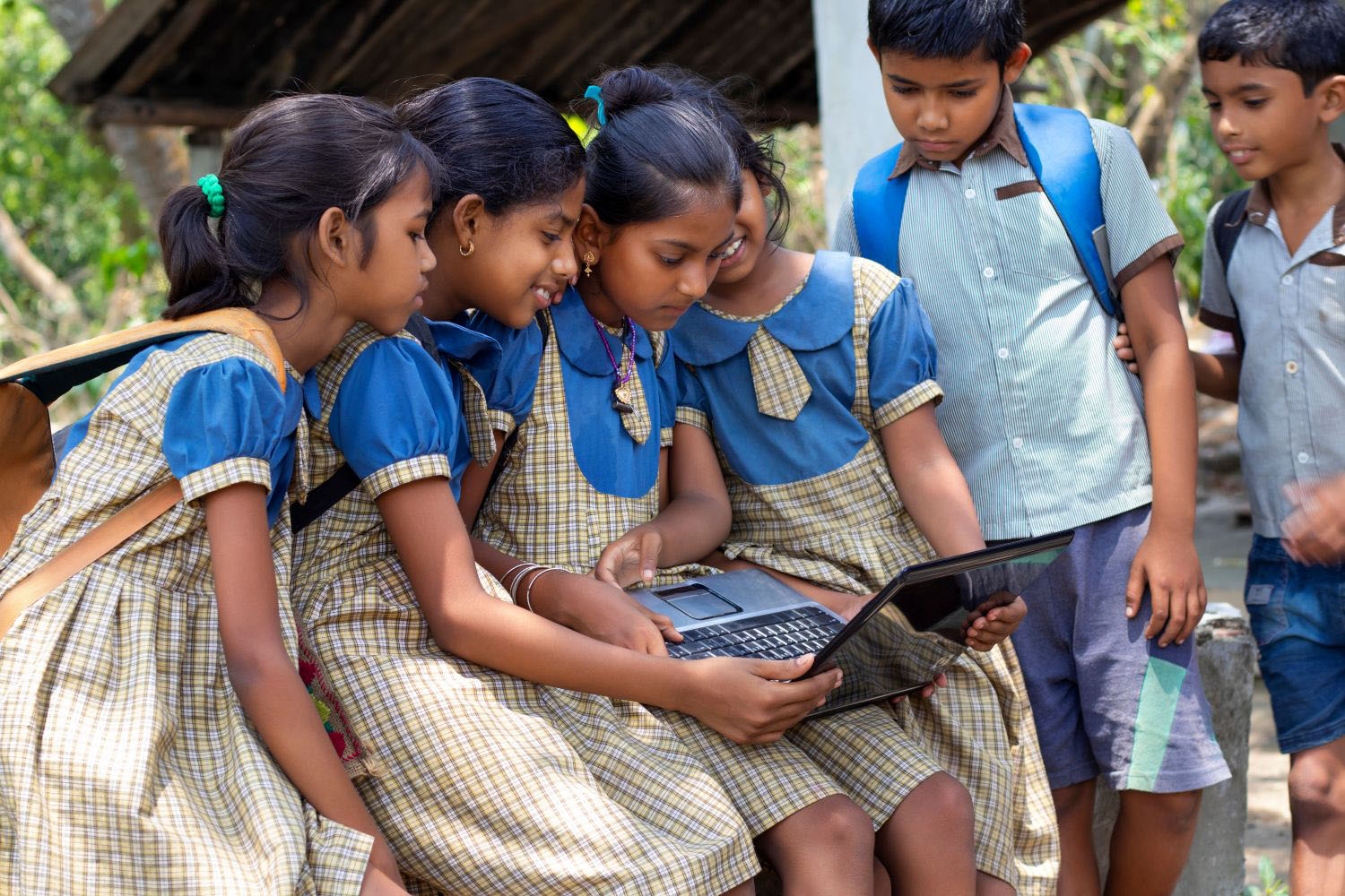 School girls operating laptop computer system in a rural area