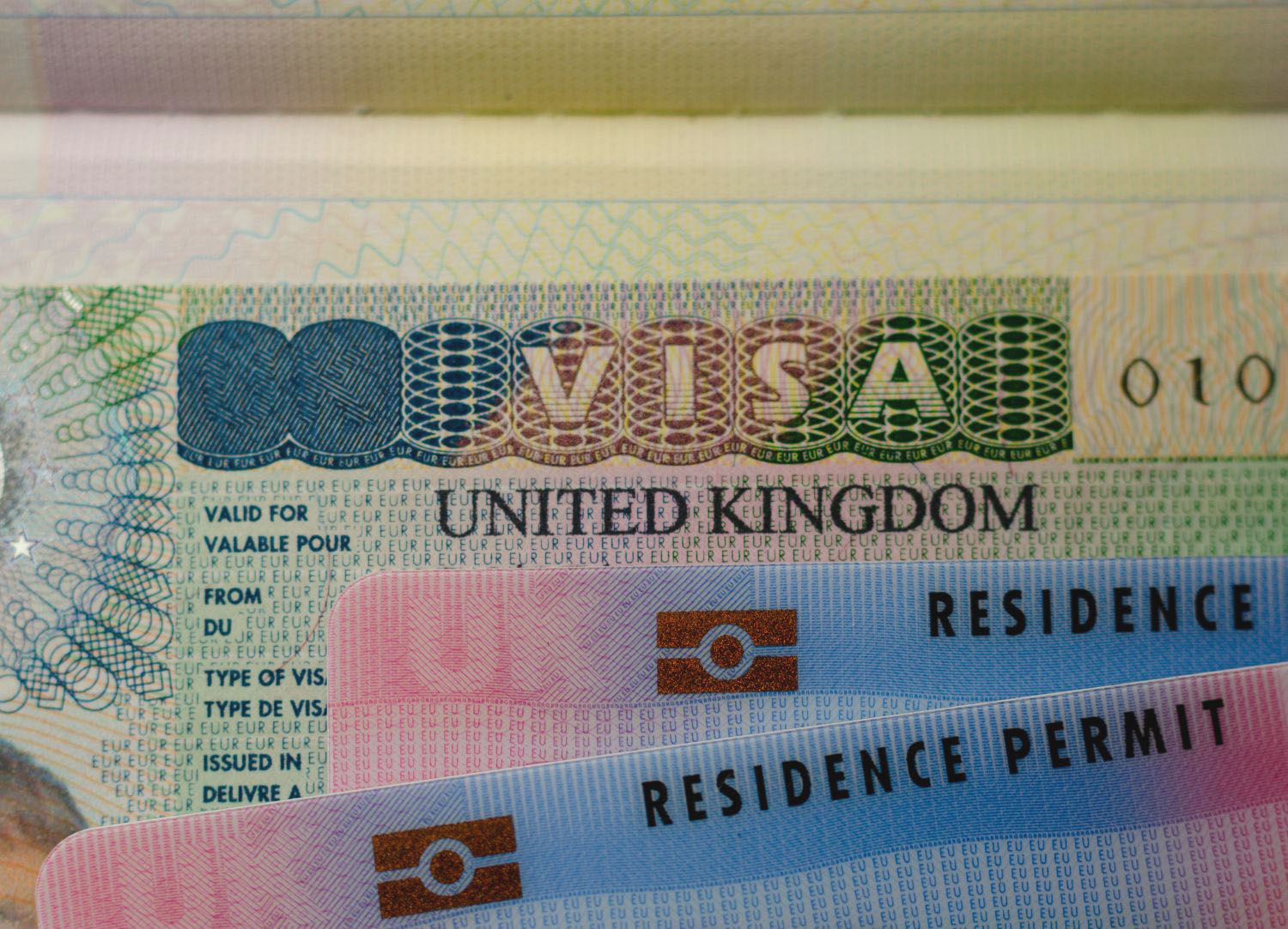 United Kingdom BRP (Biometrical Residence Permit) cards for Tier 2 work visa placed on top of UK VISA sticker in a passport