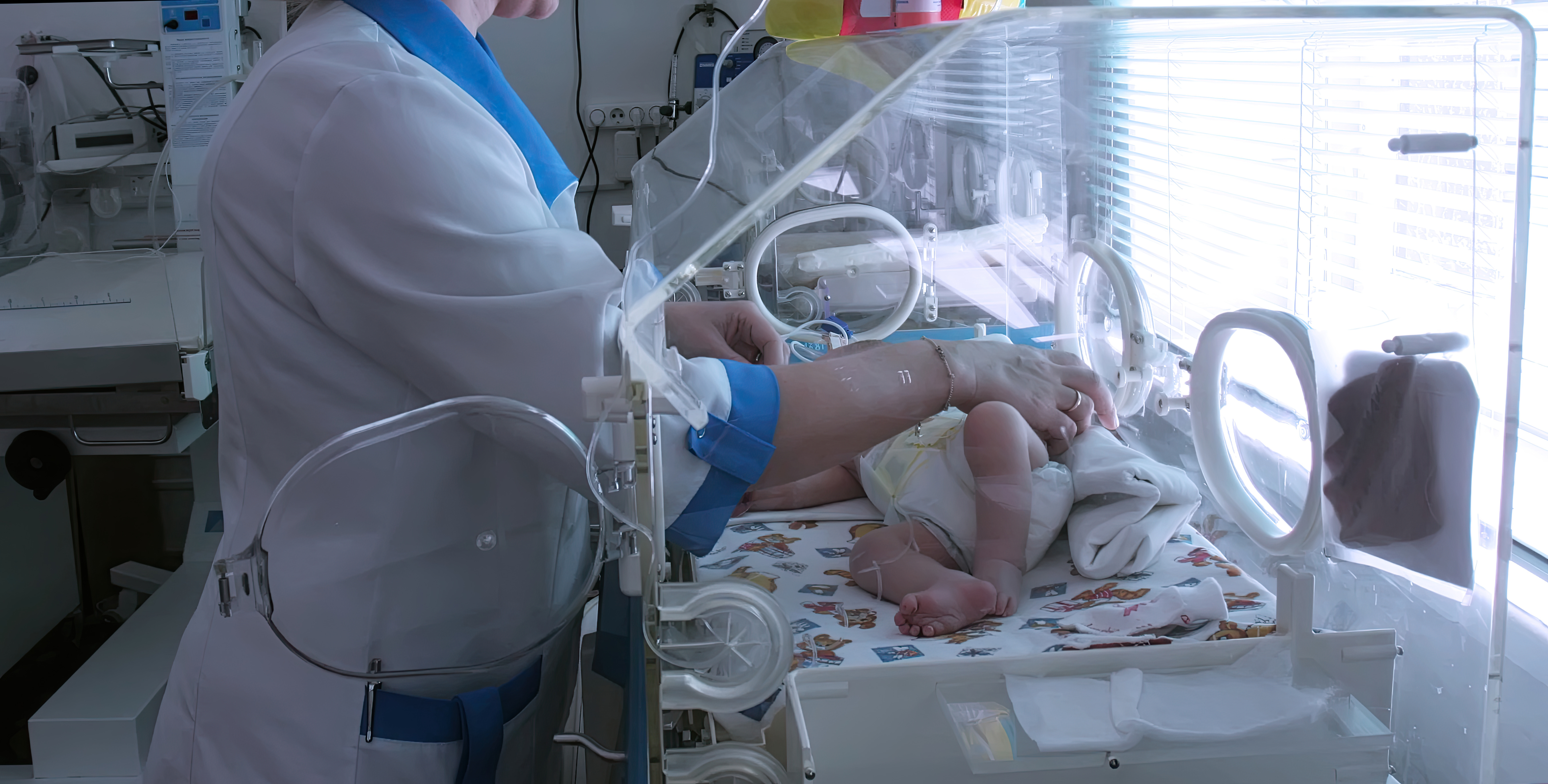 Medical staff caring for premature infant in neonatal intensive care unit during daylight hours
