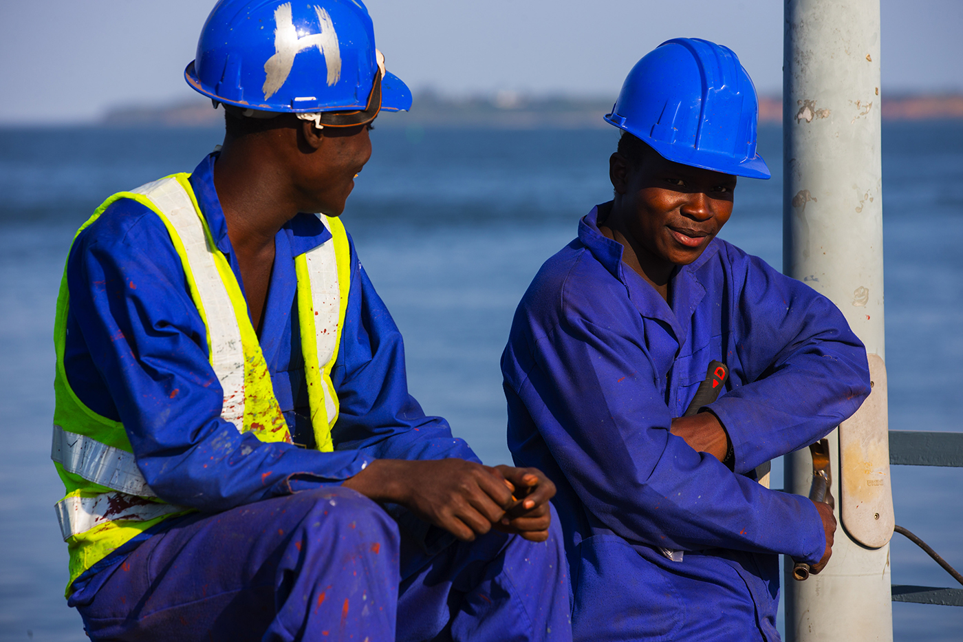 Young men working at industrial site wearing hard hats
